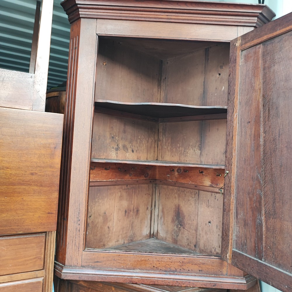 An antique brown oak hanging corner cupboard featuring a central sunburst inlaid door panel, chequered border stringing, and decorative brass hinges. View III
