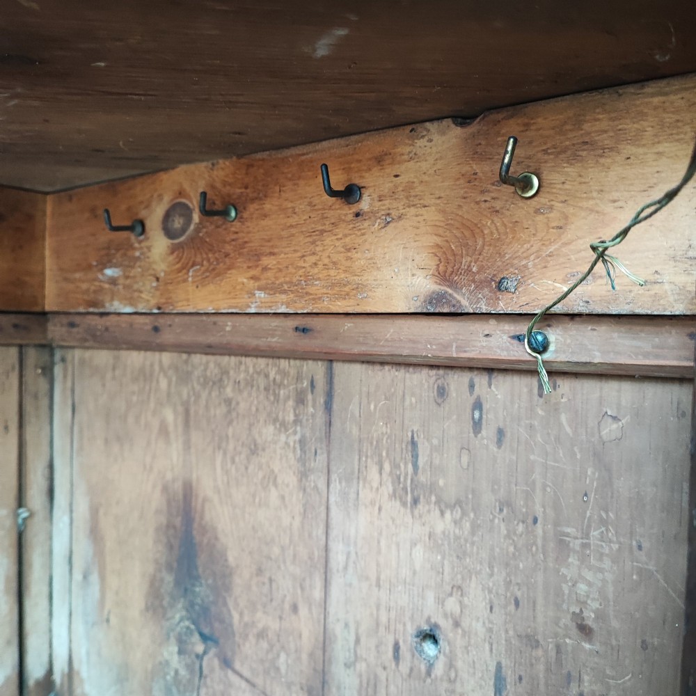 An antique brown oak hanging corner cupboard featuring a central sunburst inlaid door panel, chequered border stringing, and decorative brass hinges. View V