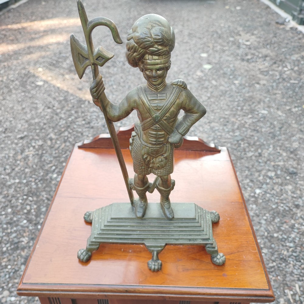 An antique cast brass doorstop depicting a Scottish Highlander soldier holding a halberd, set upon a stepped base with claw feet. View II