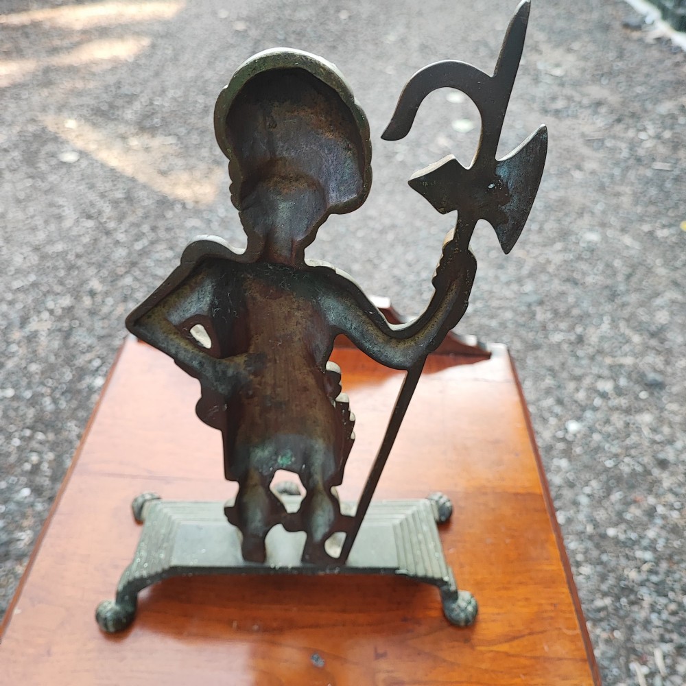 An antique cast brass doorstop depicting a Scottish Highlander soldier holding a halberd, set upon a stepped base with claw feet. View III