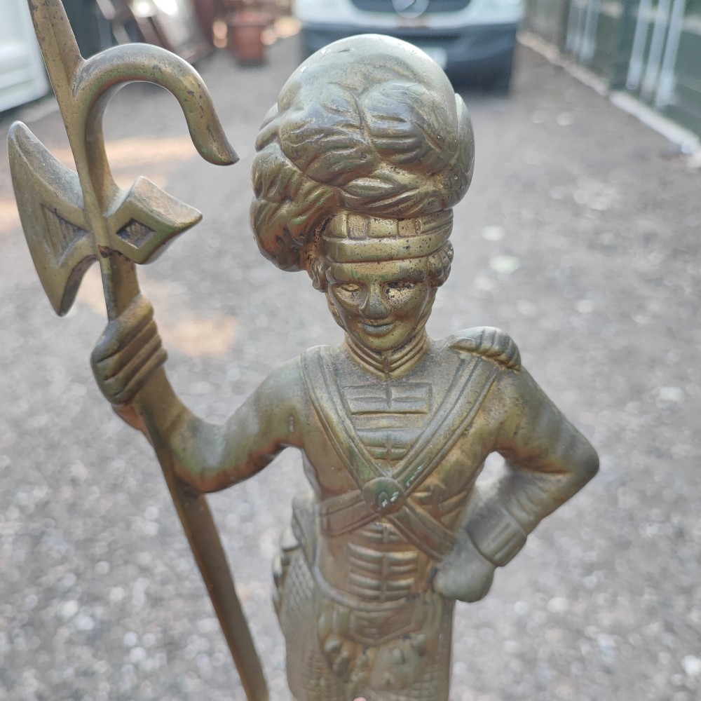 An antique cast brass doorstop depicting a Scottish Highlander soldier holding a halberd, set upon a stepped base with claw feet. View IV