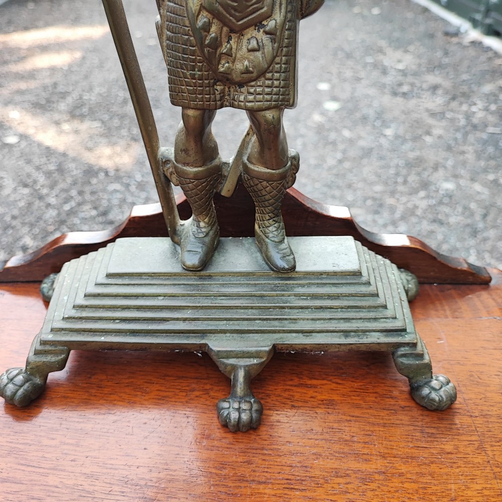 An antique cast brass doorstop depicting a Scottish Highlander soldier holding a halberd, set upon a stepped base with claw feet. View V