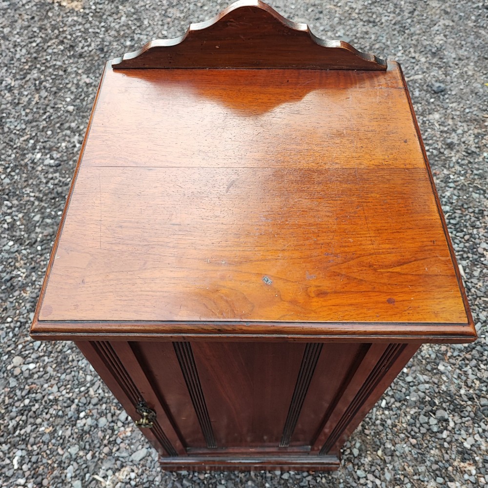 An Edwardian mahogany bedside cabinet with a shaped splashback, reeded door moulding, and a single brass drop handle. View III