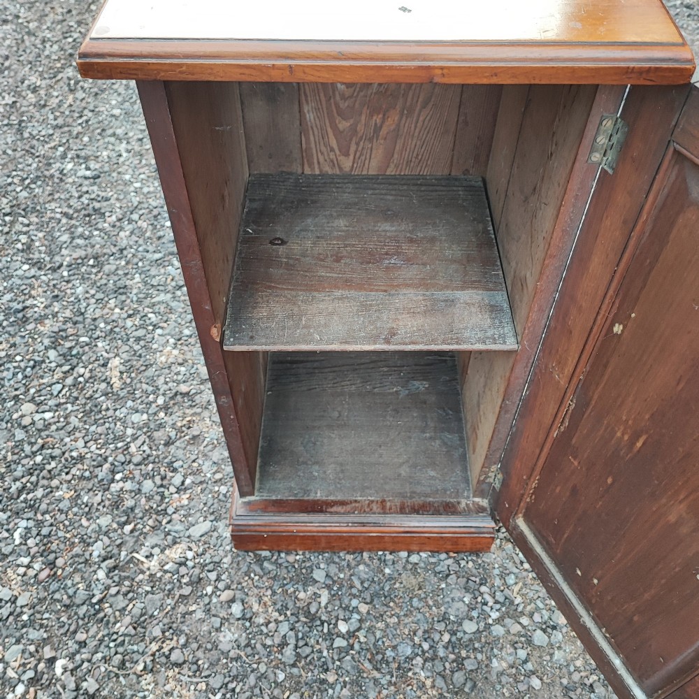 An Edwardian mahogany bedside cabinet with a shaped splashback, reeded door moulding, and a single brass drop handle. View V