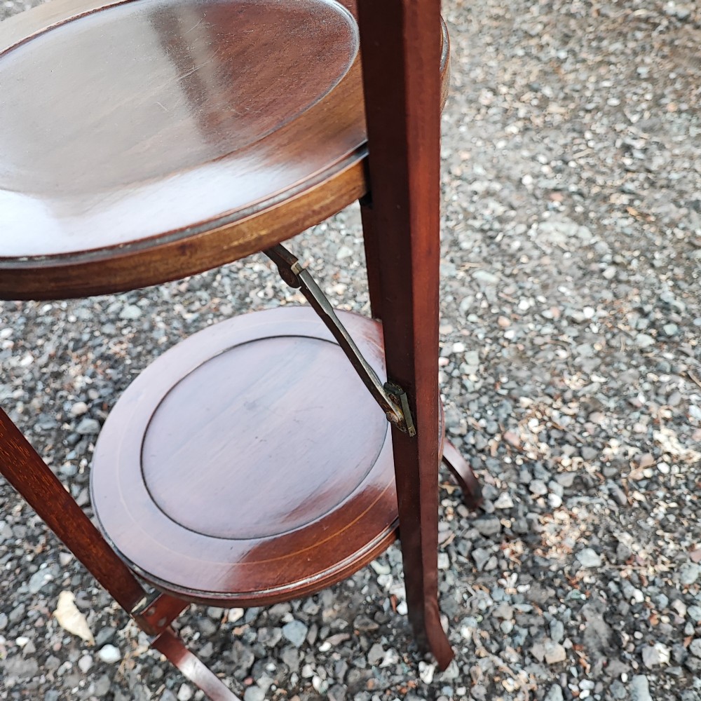 An Edwardian three-tier mahogany cake stand with boxwood string inlay, circular trays, and a arched top carrying handle. View II