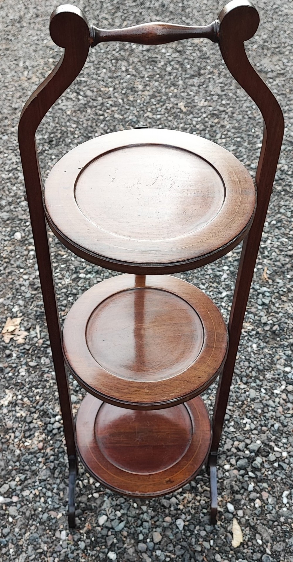 An Edwardian three-tier mahogany cake stand with boxwood string inlay, circular trays, and a arched top carrying handle. View V