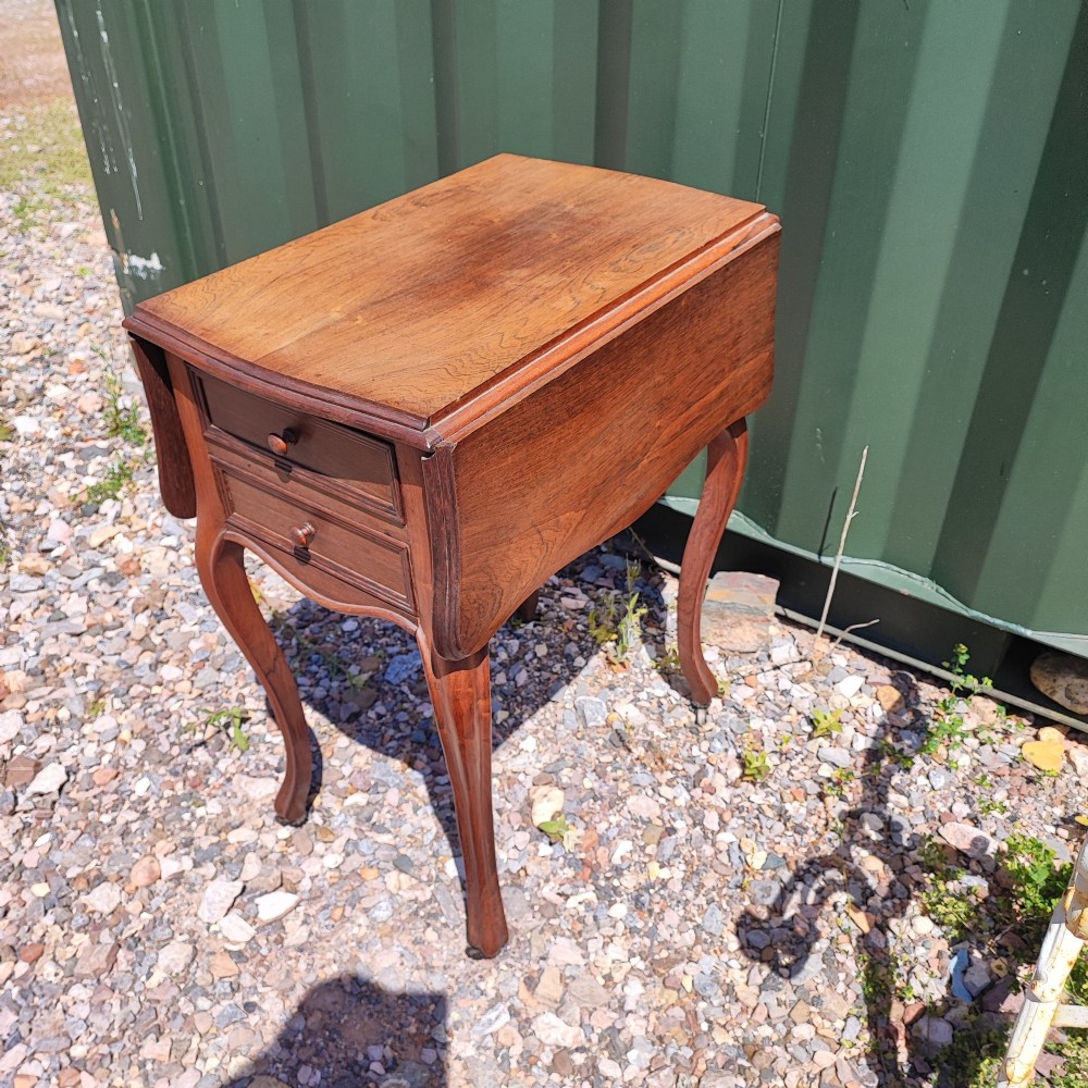 An antique rosewood drop leaf bedside table featuring cabriole legs and two front drawers with small wooden knobs.
