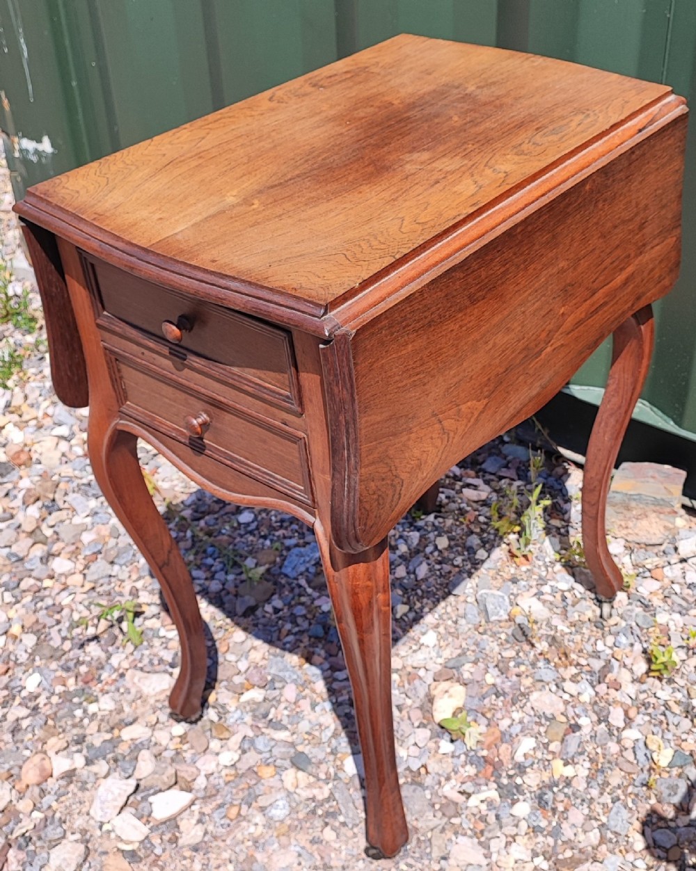 An antique rosewood drop leaf bedside table featuring cabriole legs and two front drawers with small wooden knobs. View II
