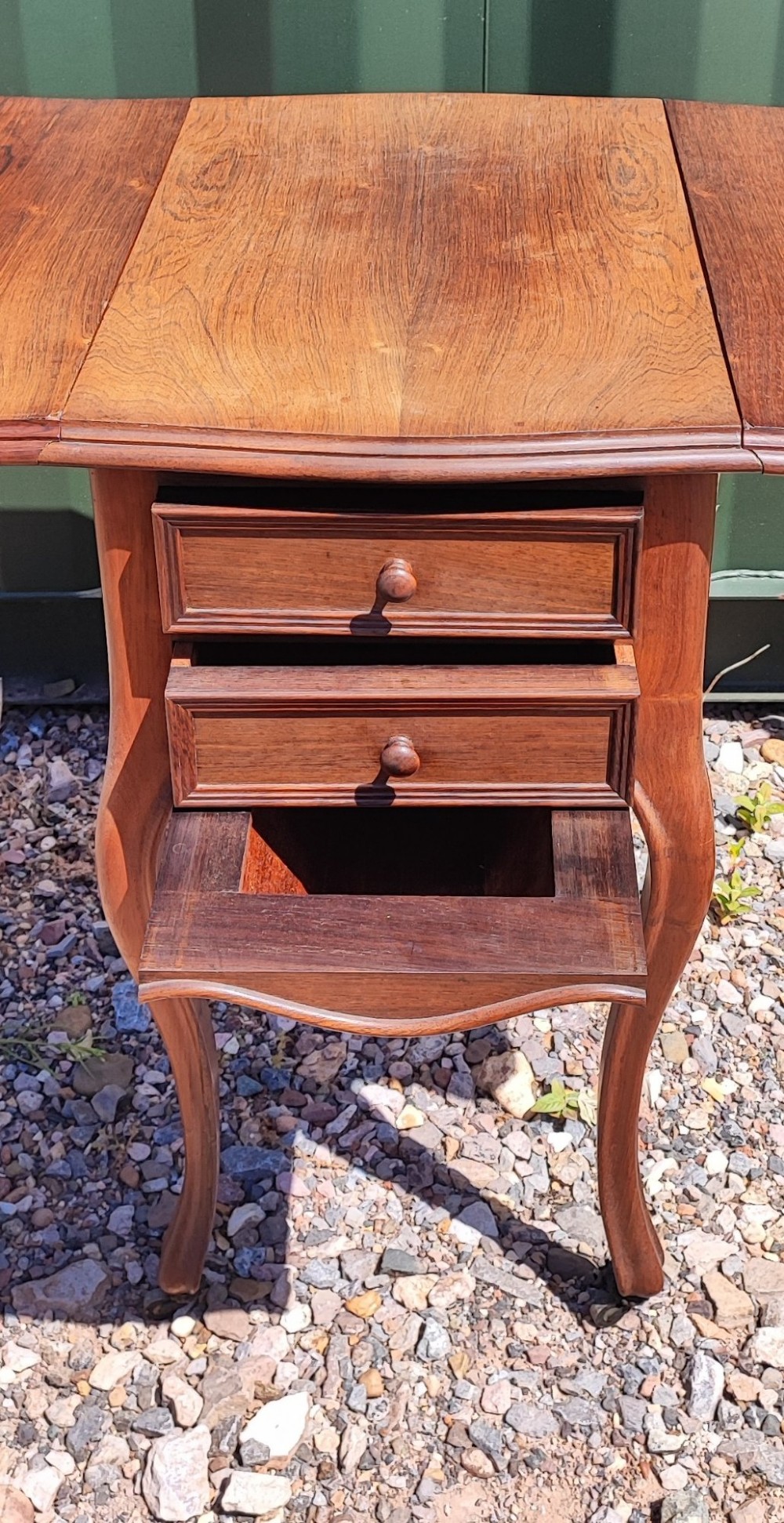 An antique rosewood drop leaf bedside table featuring cabriole legs and two front drawers with small wooden knobs. View III