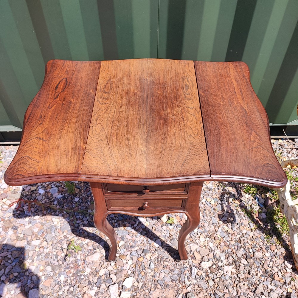 An antique rosewood drop leaf bedside table featuring cabriole legs and two front drawers with small wooden knobs. View VII