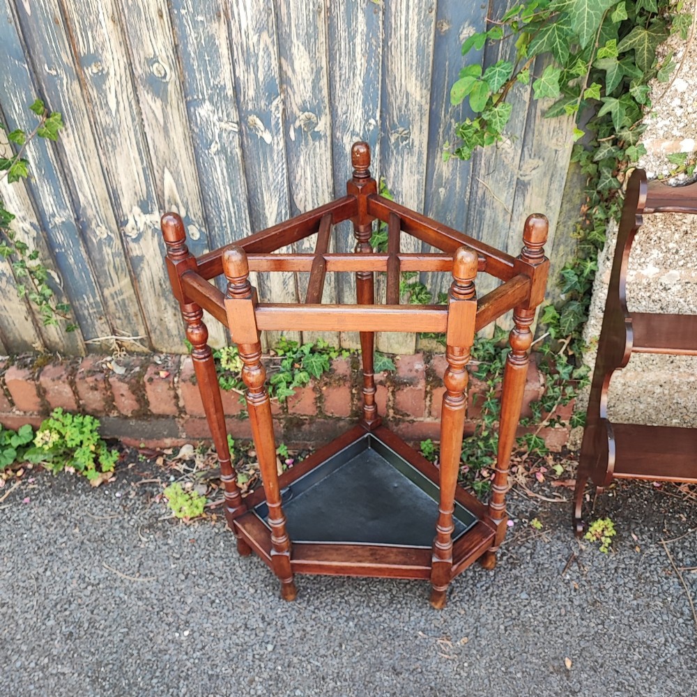 A Victorian mahogany triangular corner umbrella stand featuring turned posts, decorative finials, a compartmentalised top frame, and a dark metal drip tray base. View II