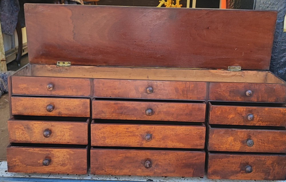 A Regency mahogany watchmaker chest featuring a top hinged compartment above multiple small drawers with turned wooden handles.