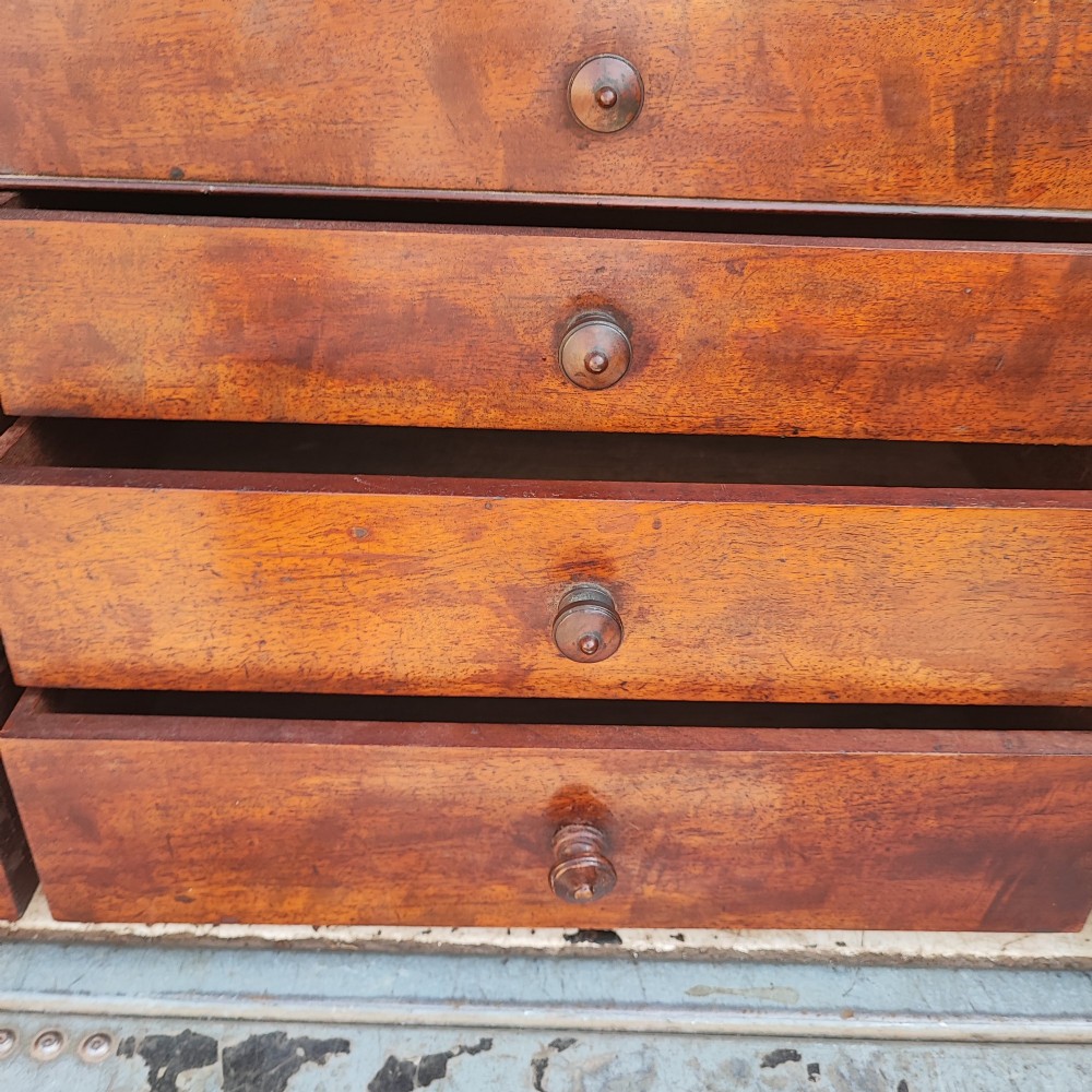 A Regency mahogany watchmaker chest featuring a top hinged compartment above multiple small drawers with turned wooden handles. View II