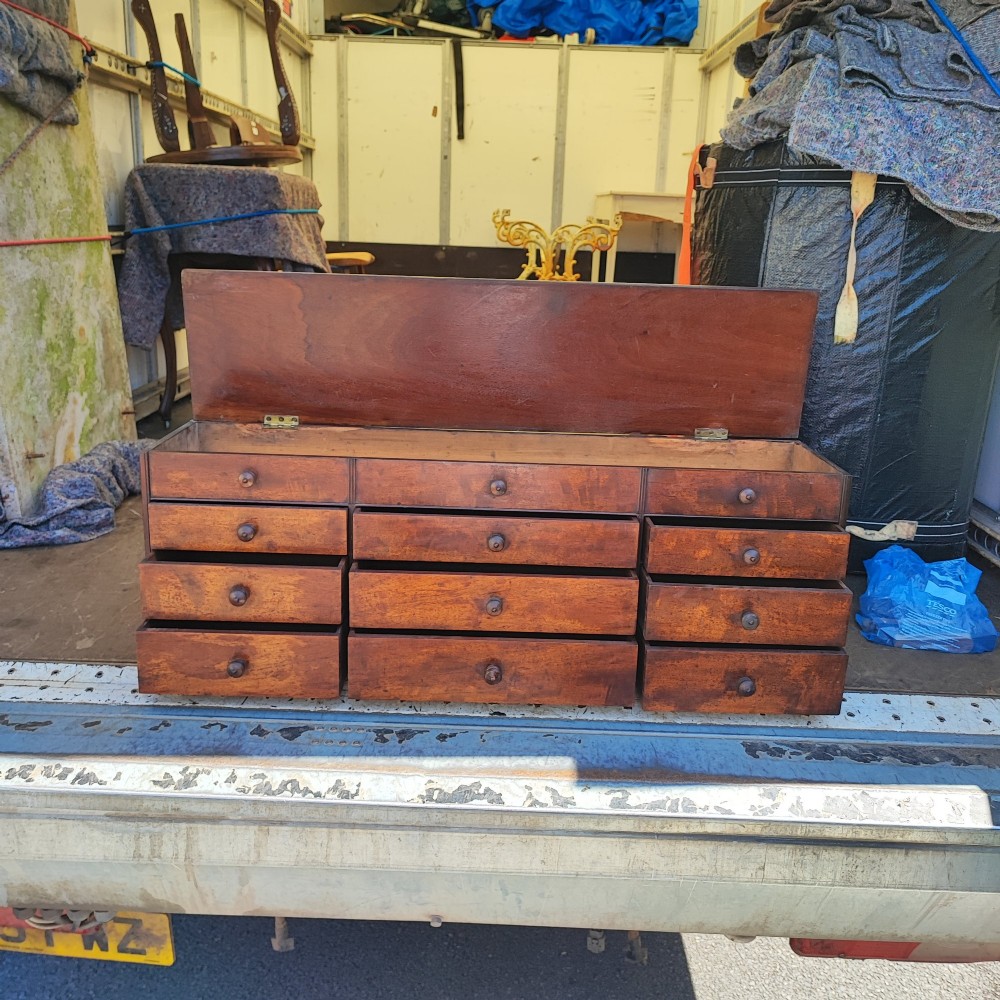A Regency mahogany watchmaker chest featuring a top hinged compartment above multiple small drawers with turned wooden handles. View III