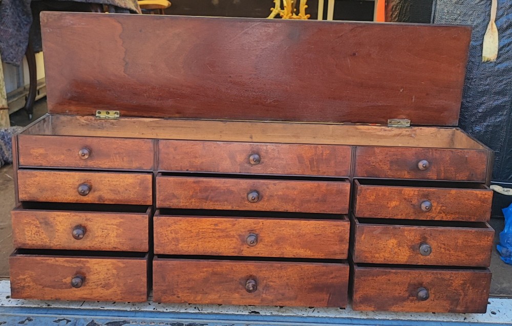 A Regency mahogany watchmaker chest featuring a top hinged compartment above multiple small drawers with turned wooden handles. View VI
