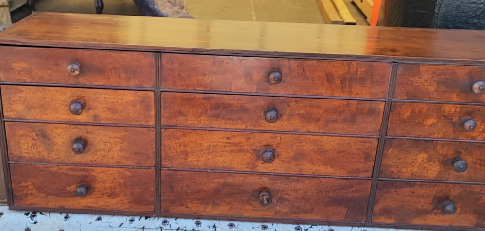 A Regency mahogany watchmaker chest featuring a top hinged compartment above multiple small drawers with turned wooden handles. View VII
