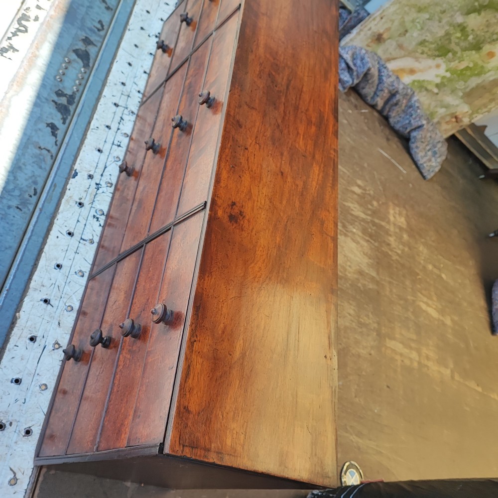 A Regency mahogany watchmaker chest featuring a top hinged compartment above multiple small drawers with turned wooden handles. View X