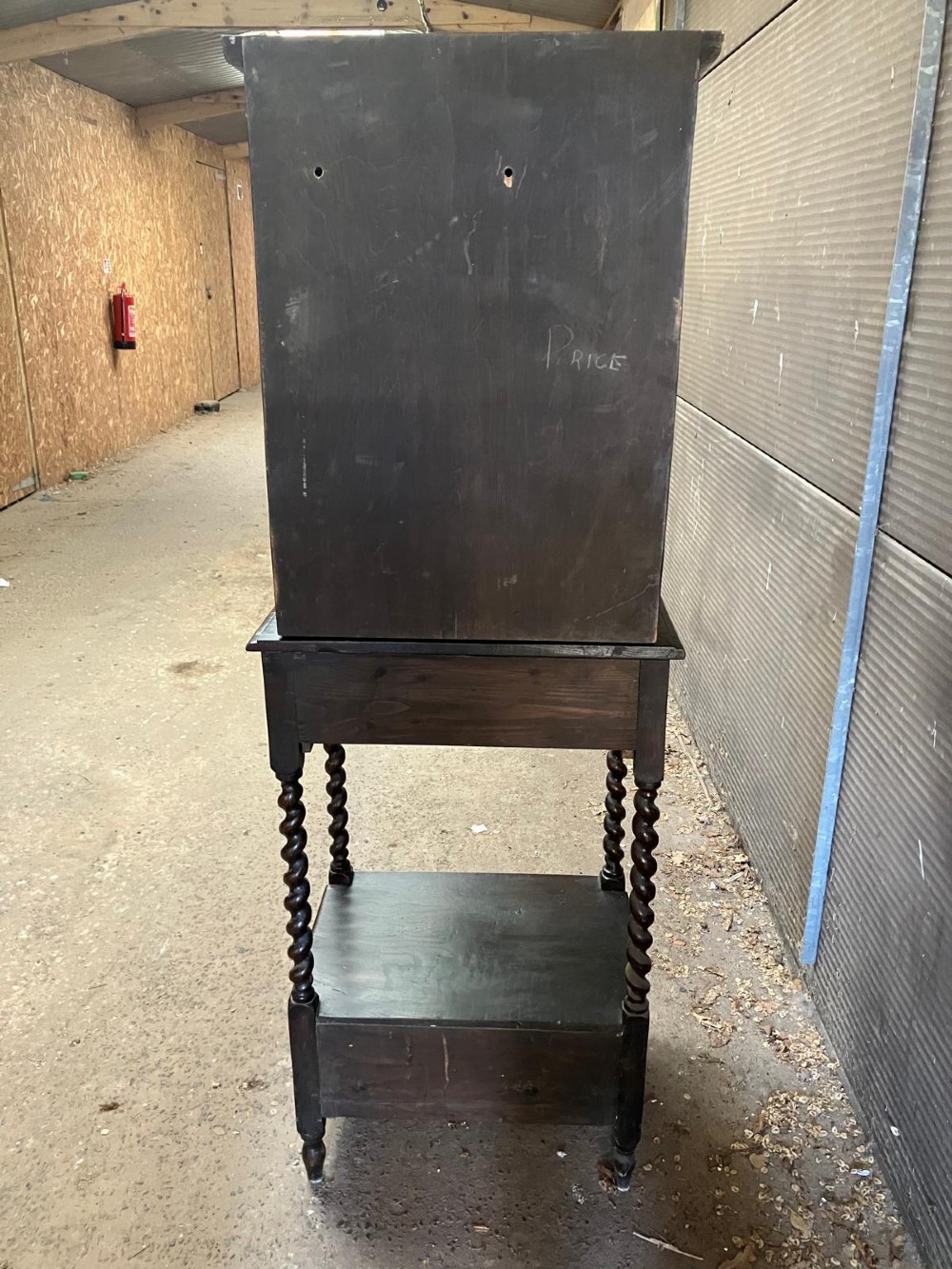 An antique dark carved oak hall cabinet featuring an upper cupboard door with Gothic arched relief carving, two drawers with brass drop handles, and turned barley twist legs. View III