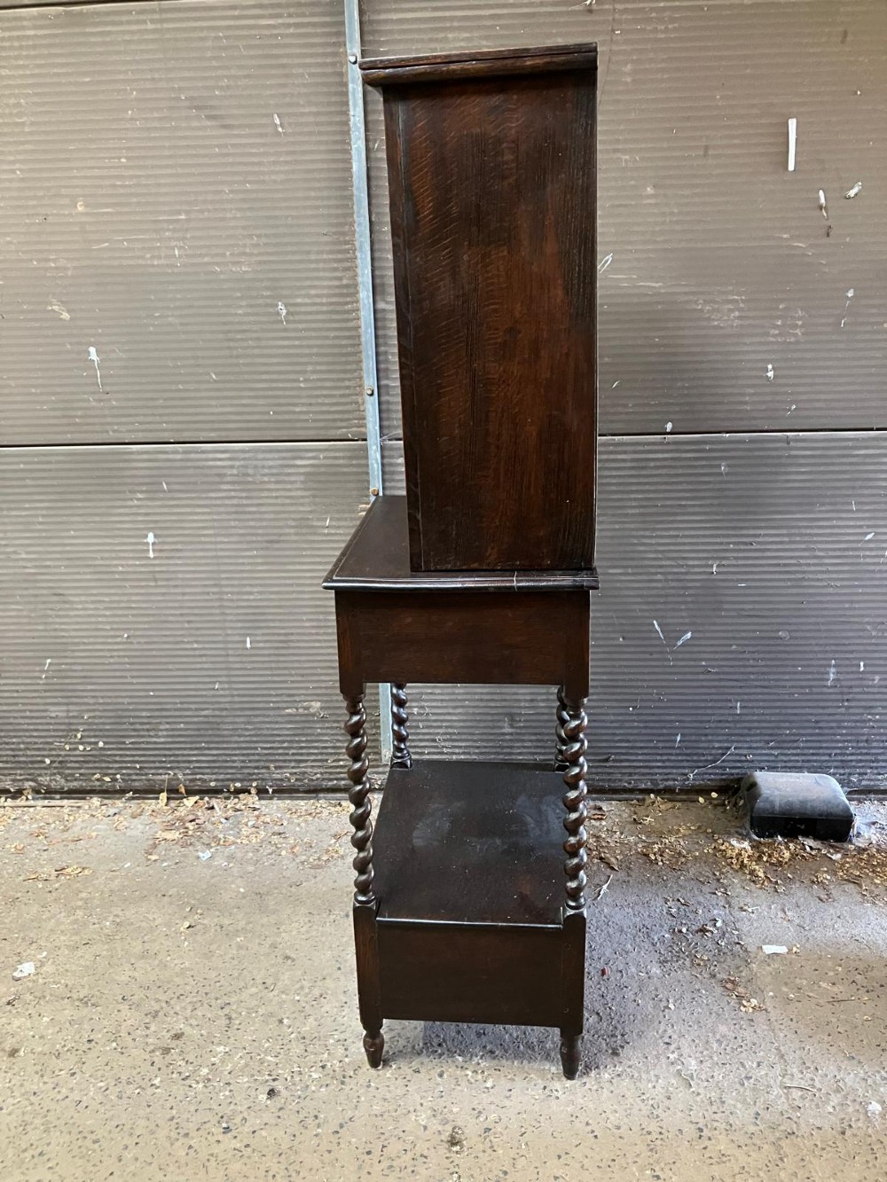 An antique dark carved oak hall cabinet featuring an upper cupboard door with Gothic arched relief carving, two drawers with brass drop handles, and turned barley twist legs. View IV