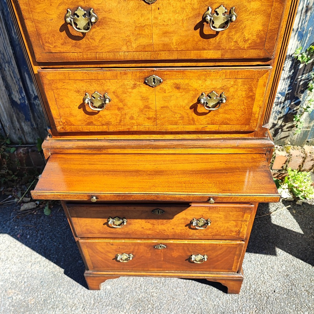 A tall antique walnut chest on chest featuring an arched pediment top with sunburst inlay, brass drop handles, and bracket feet. View II