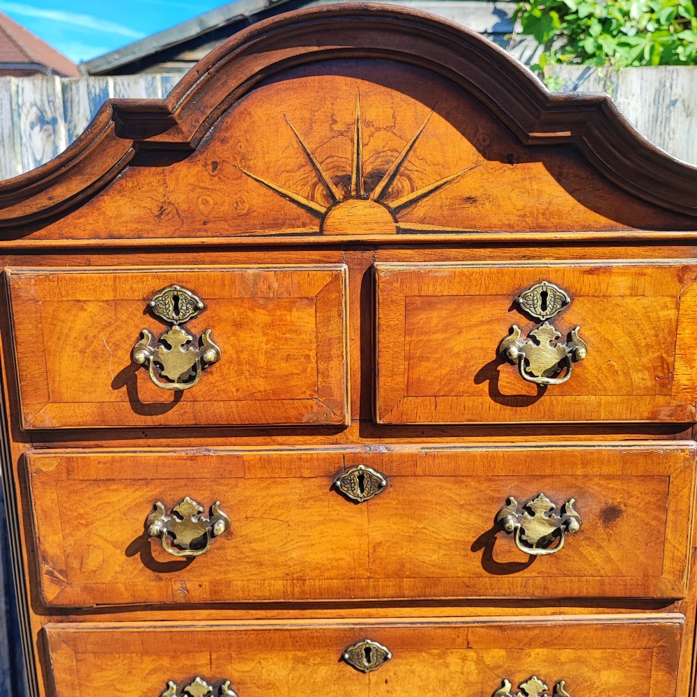 A tall antique walnut chest on chest featuring an arched pediment top with sunburst inlay, brass drop handles, and bracket feet. View III