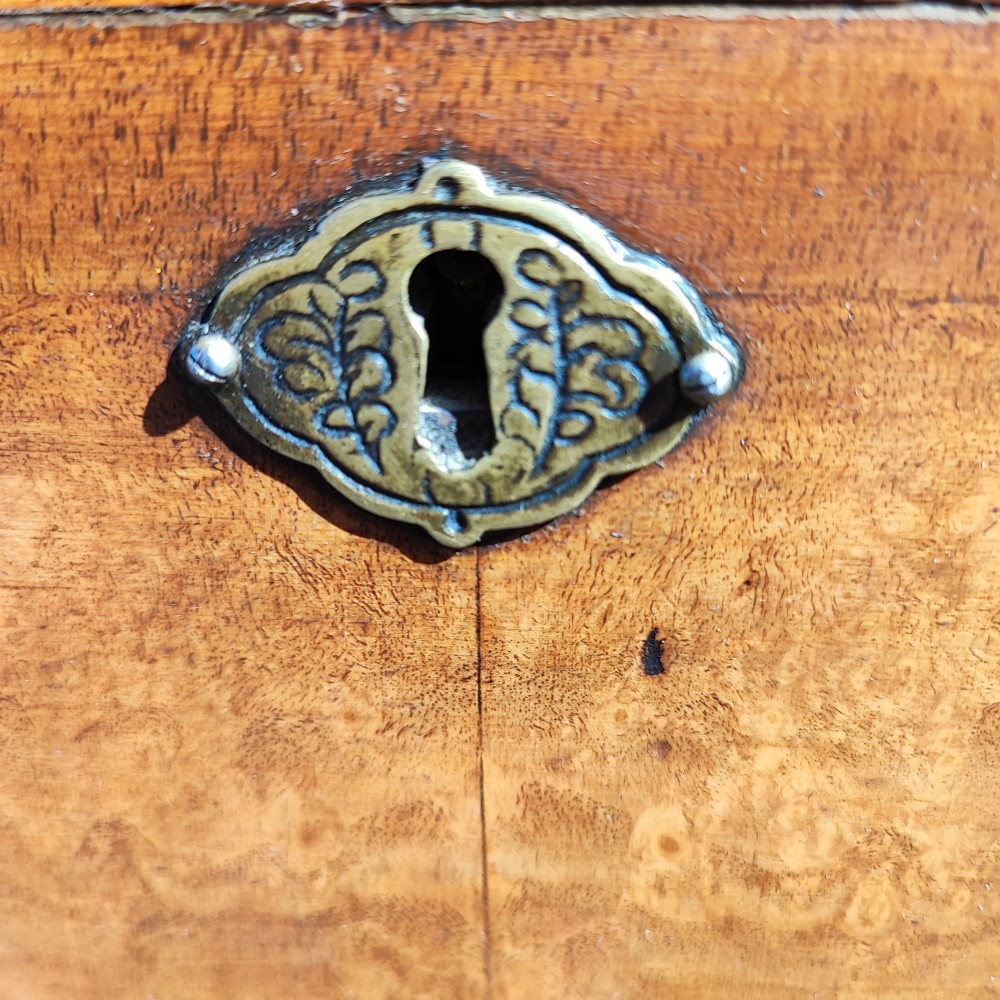 A tall antique walnut chest on chest featuring an arched pediment top with sunburst inlay, brass drop handles, and bracket feet. View VI