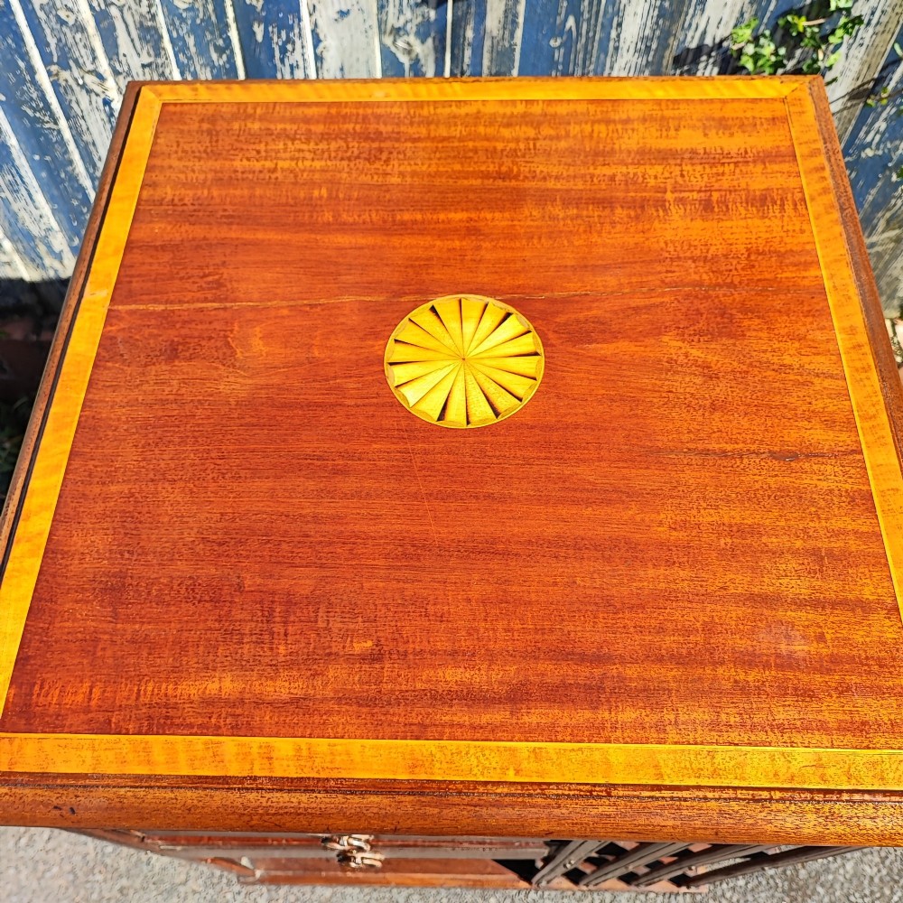 An Edwardian inlaid mahogany revolving bookcase featuring a square top with a central starburst patera inlay, three small drawers with brass ring handles, and vertical timber side slats. View II