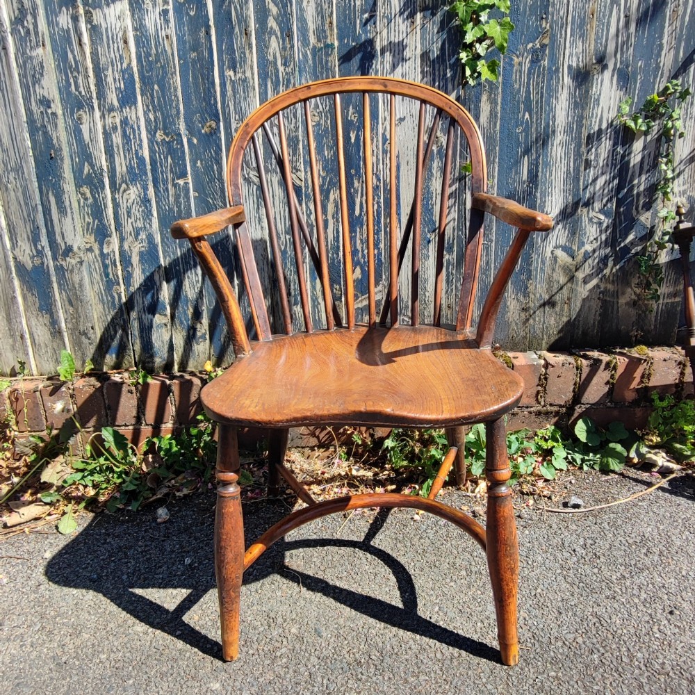 An antique wooden Windsor armchair crafted from yew and elm, featuring a hoop back with thin spindles, curved armrests, a shaped saddle seat, turned legs, and a rounded stretcher. View VIII