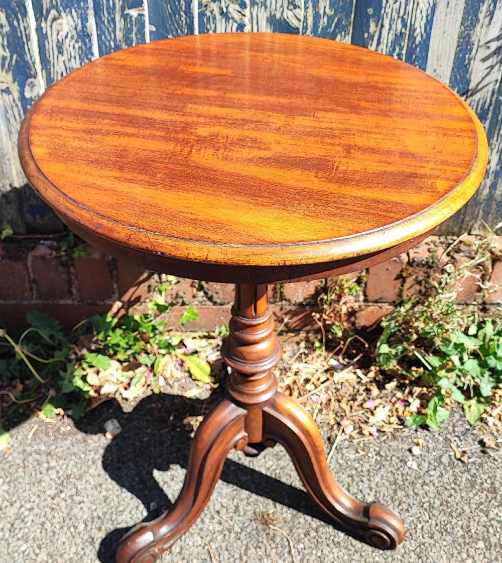 A round mahogany wine table featuring a smooth circular top, turned central pedestal column, and three carved legs ending in scroll feet. View II
