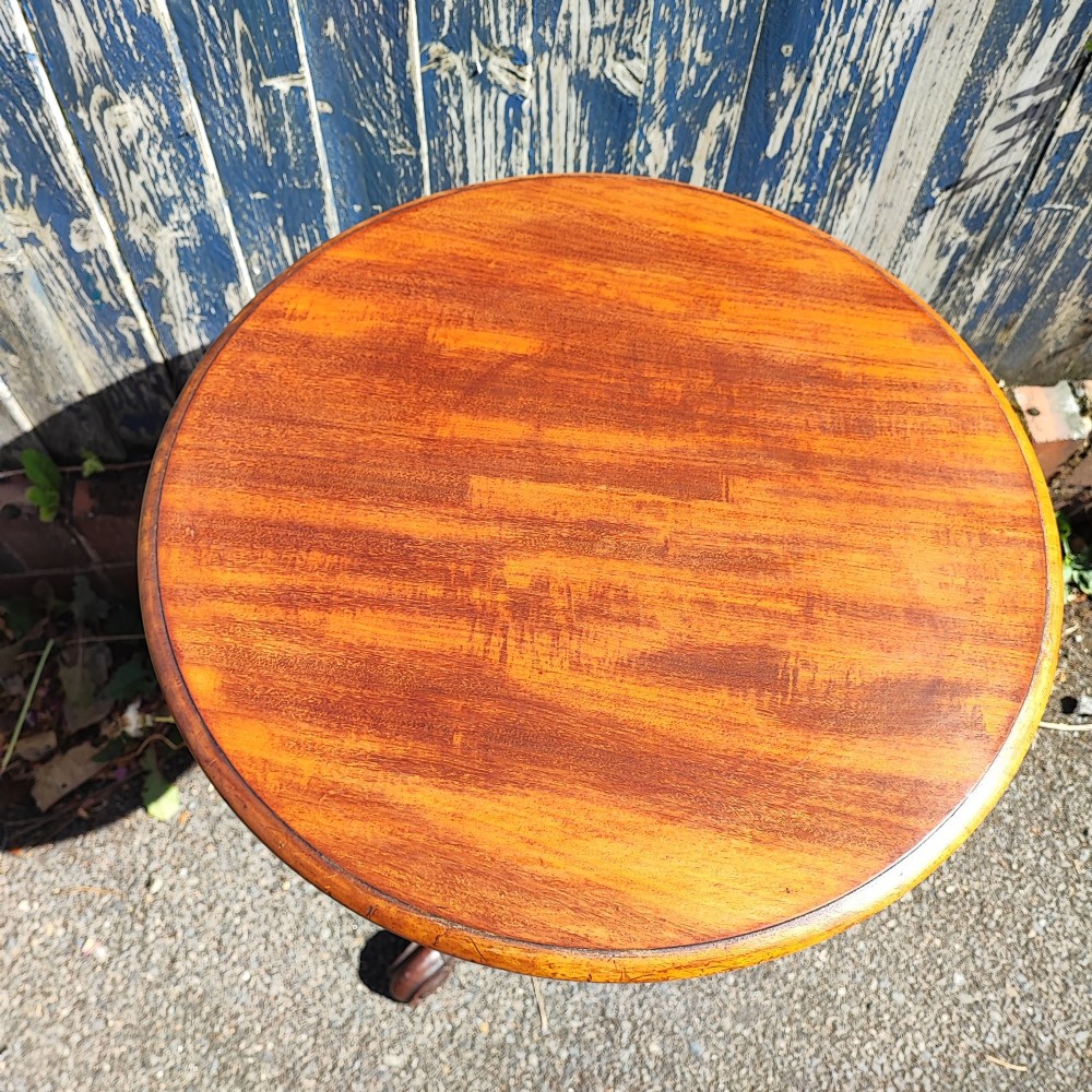 A round mahogany wine table featuring a smooth circular top, turned central pedestal column, and three carved legs ending in scroll feet. View III