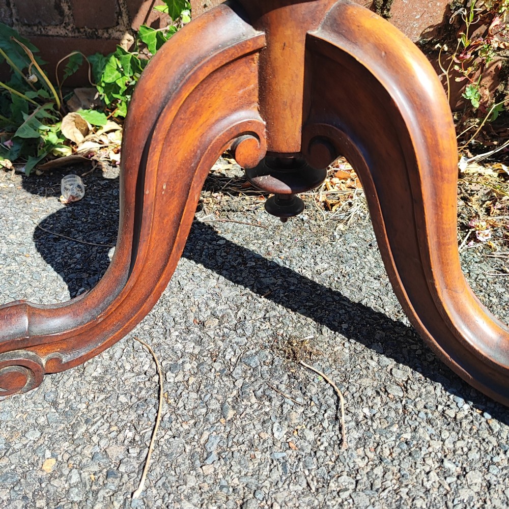 A round mahogany wine table featuring a smooth circular top, turned central pedestal column, and three carved legs ending in scroll feet. View IV