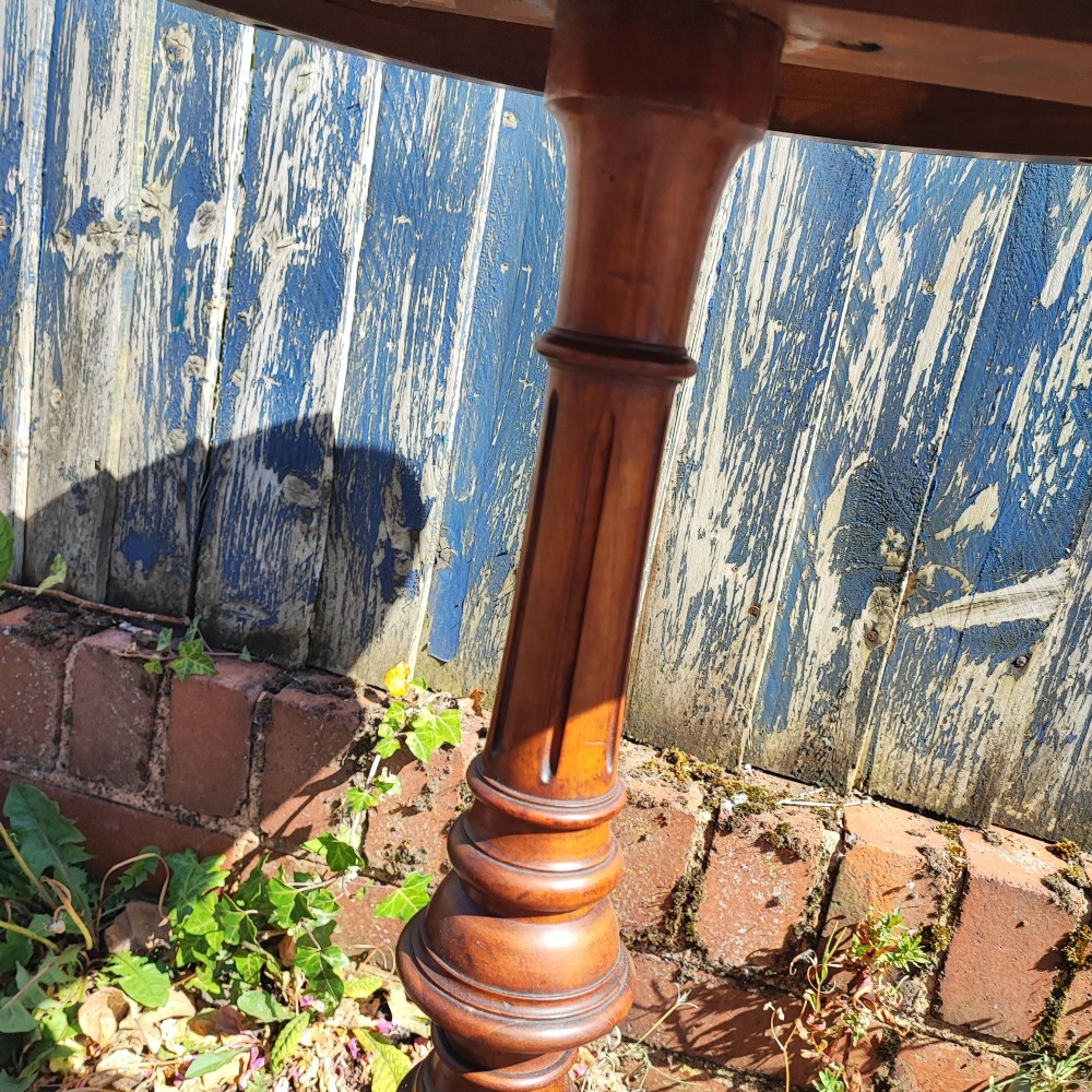 A round mahogany wine table featuring a smooth circular top, turned central pedestal column, and three carved legs ending in scroll feet. View V