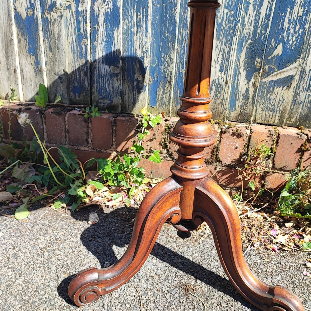 A round mahogany wine table featuring a smooth circular top, turned central pedestal column, and three carved legs ending in scroll feet. View VI