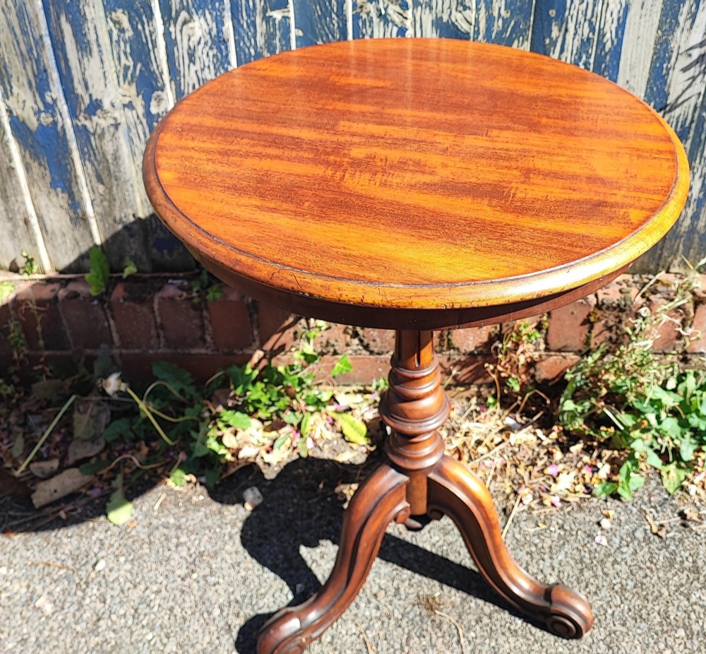 A round mahogany wine table featuring a smooth circular top, turned central pedestal column, and three carved legs ending in scroll feet. View VII
