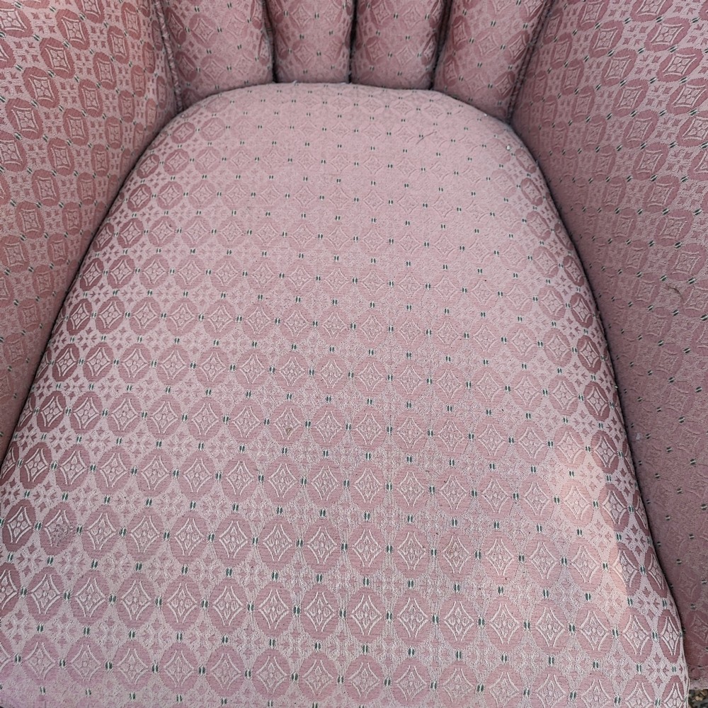 A Regency style barrel back wing armchair upholstered in patterned dusky pink fabric with channel tufting and turned wooden front legs on castors. View VI