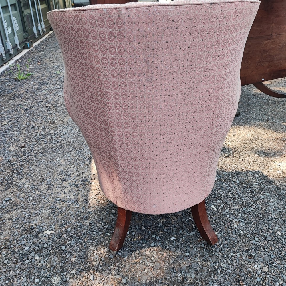 A Regency style barrel back wing armchair upholstered in patterned dusky pink fabric with channel tufting and turned wooden front legs on castors. View VII