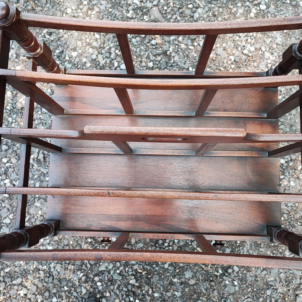 An antique Regency mahogany Canterbury featuring slatted vertical dividers, a central carrying handle, a single base drawer, and turned legs with brass castors. View III