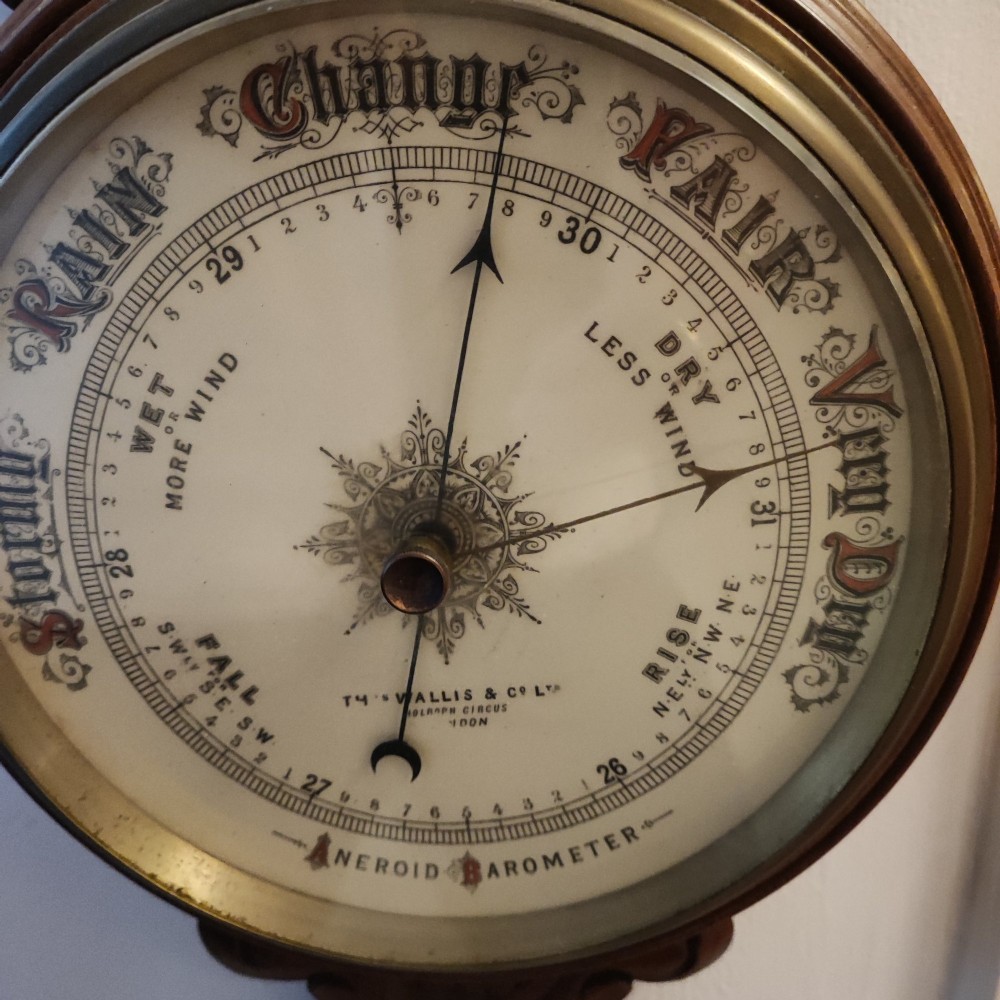 A carved Victorian mahogany aneroid wall barometer featuring top scrollwork, an integrated thermometer trunk, and a circular brass-rimmed dial. View VIII