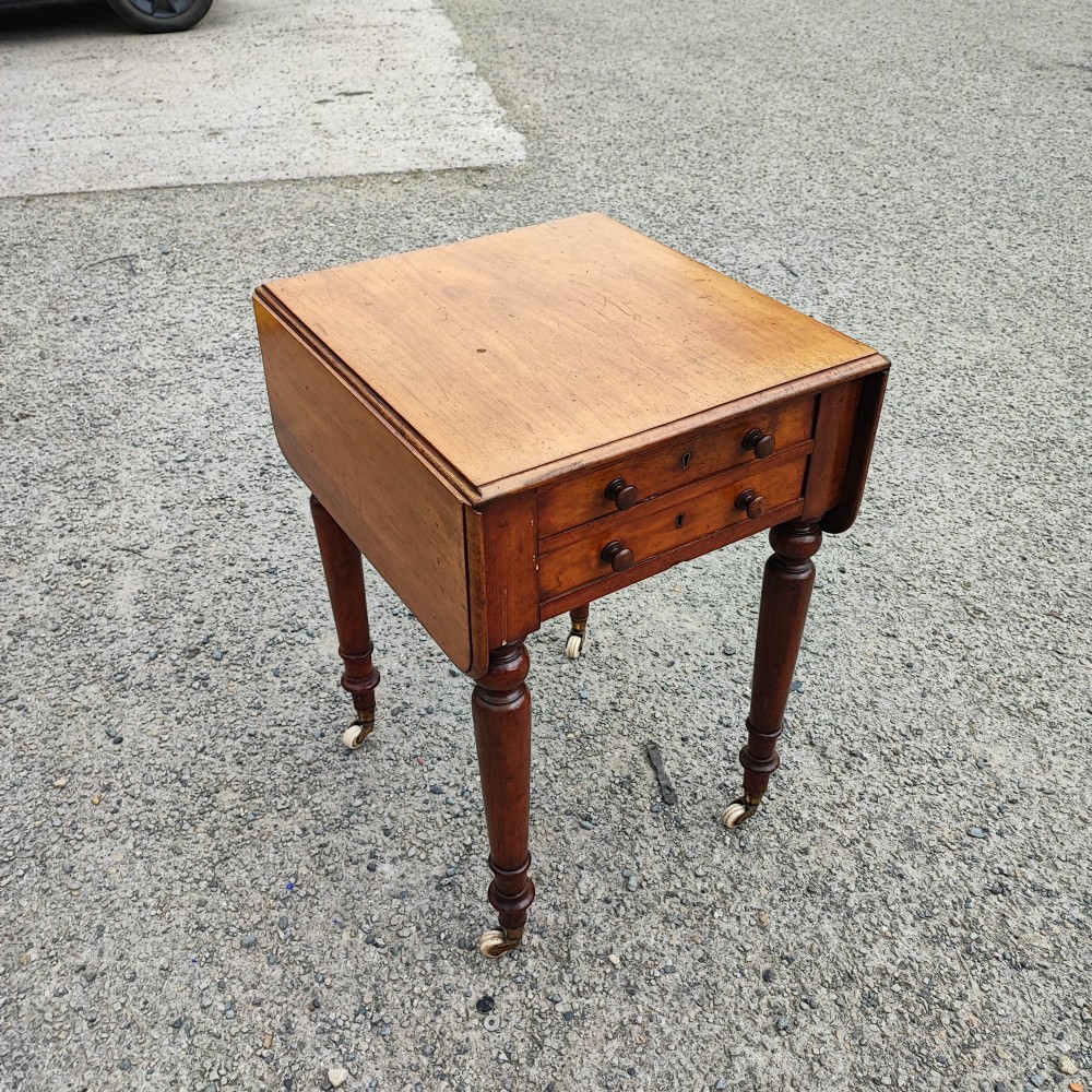 A warm brown mahogany Pembroke table featuring two drop-down leaves, two front drawers with round knobs, and turned legs fitted with castors. View VIII