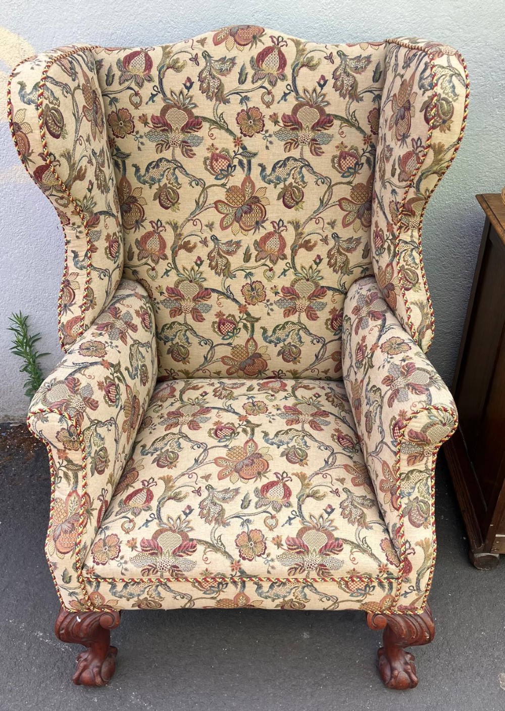 A high-back wing chair featuring floral tapestry upholstery, rolled arms, braided edge trim, and carved mahogany cabriole front legs with ball and claw feet. View III