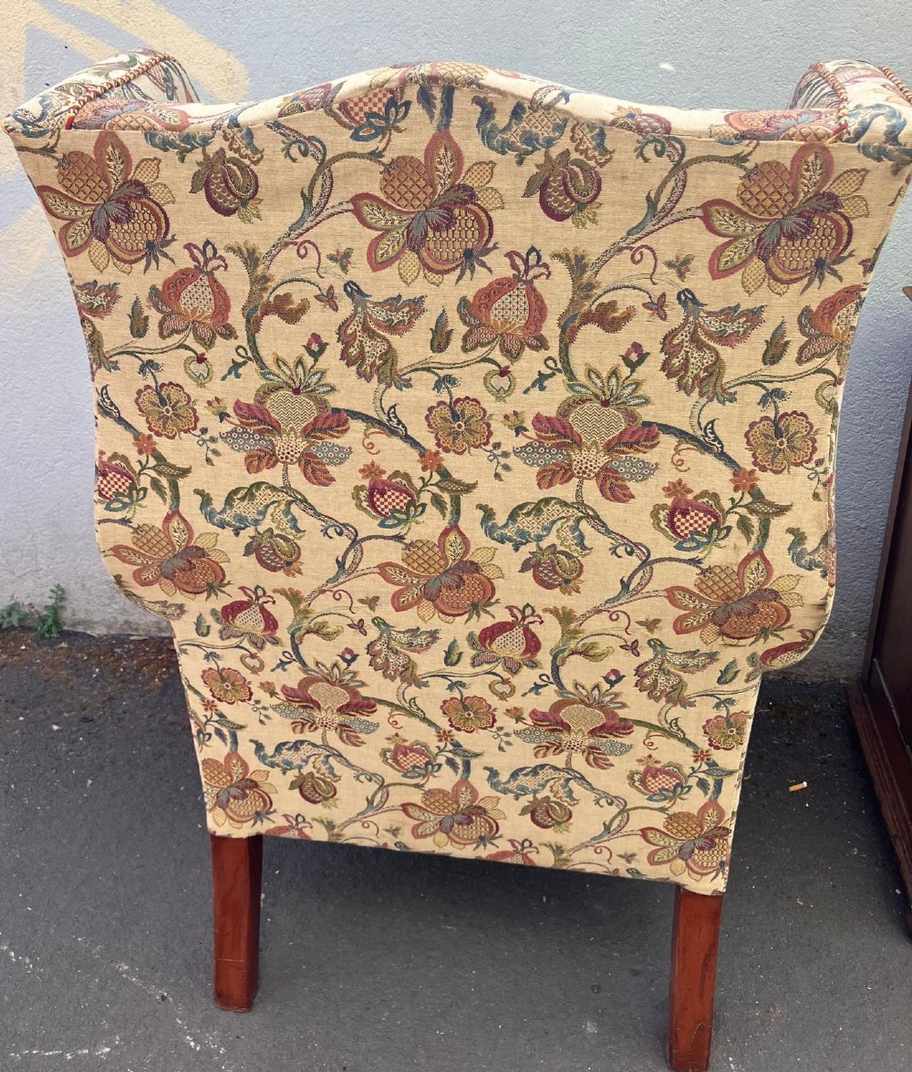 A high-back wing chair featuring floral tapestry upholstery, rolled arms, braided edge trim, and carved mahogany cabriole front legs with ball and claw feet. View V