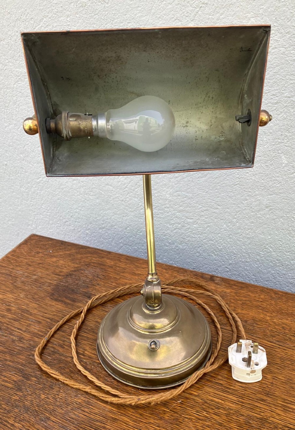 An antique brass desk lamp featuring a curved adjustable arm, a weighted stepped base, and a pivoting brass shade. View V