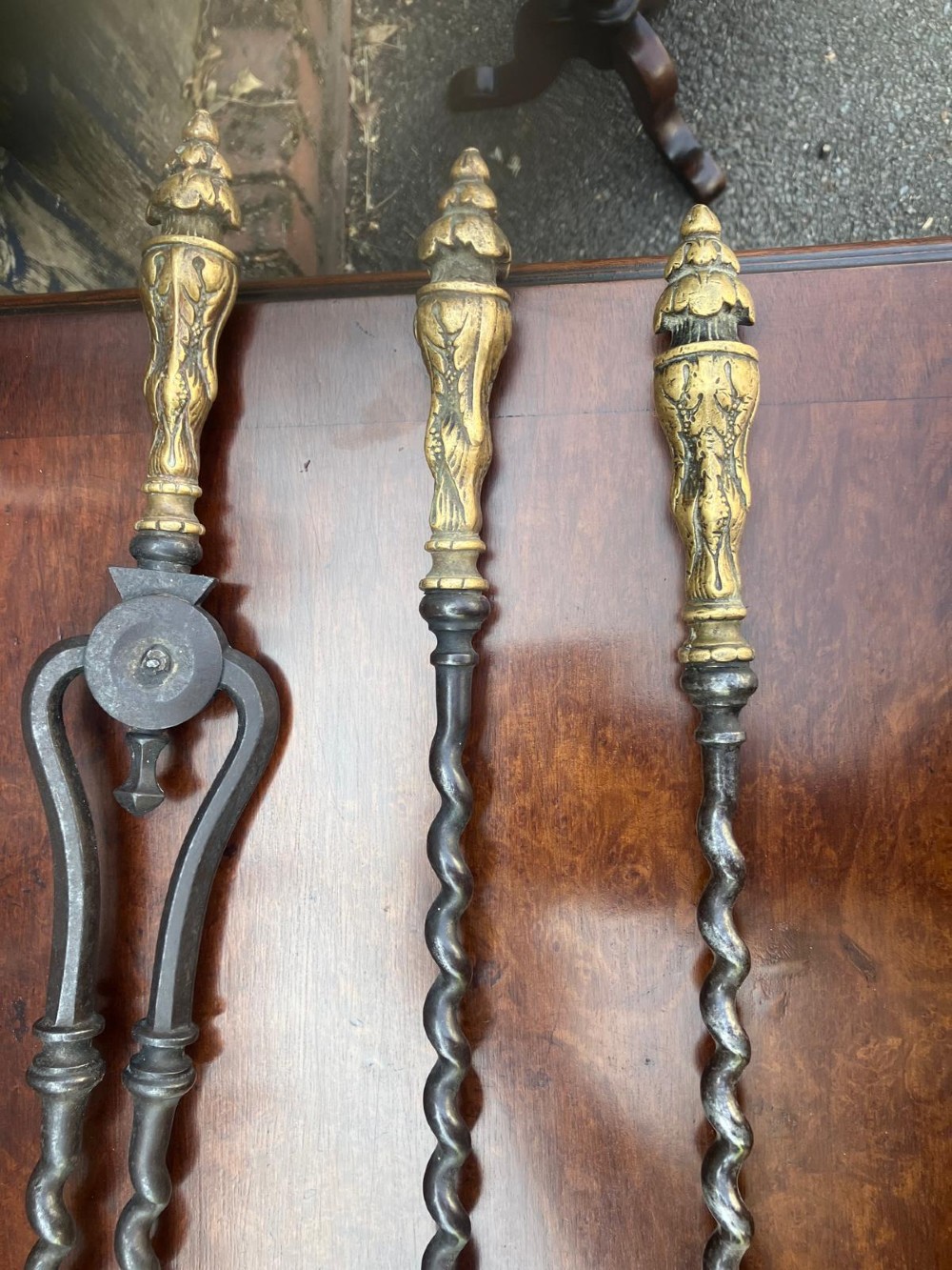 A set of three Regency fire irons featuring a poker, pierced shovel, and tongs with twisted steel shafts and cast brass handles. View II