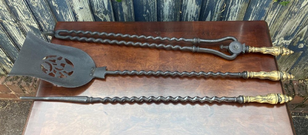 A set of three Regency fire irons featuring a poker, pierced shovel, and tongs with twisted steel shafts and cast brass handles. View IV