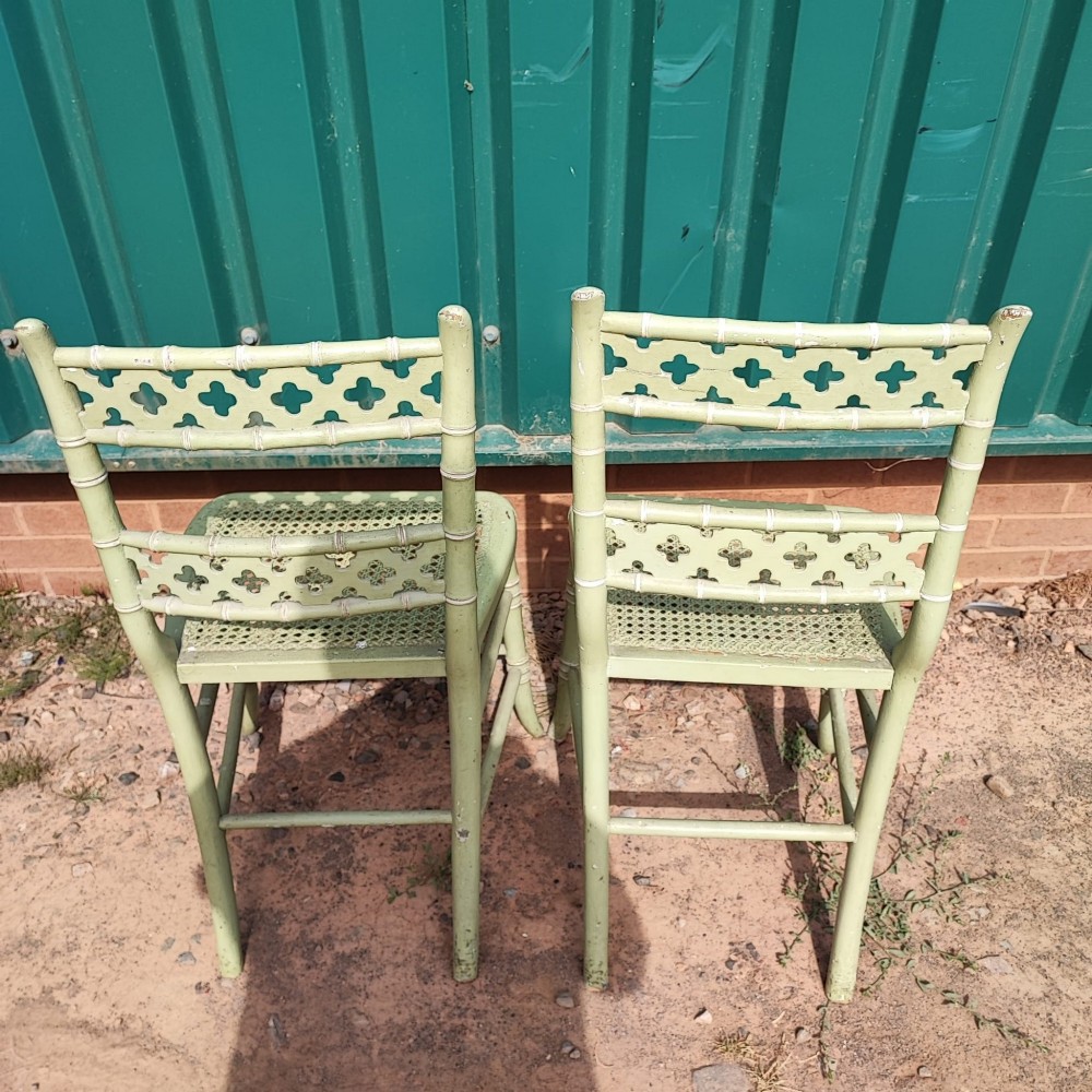 A pair of pale green painted side chairs featuring faux bamboo turned wooden frames, latticework backrests, and woven cane seats. View V