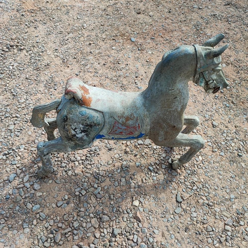 A cast metal antique carousel horse displaying distressed blue, red, and white paint with a weathered surface patina.