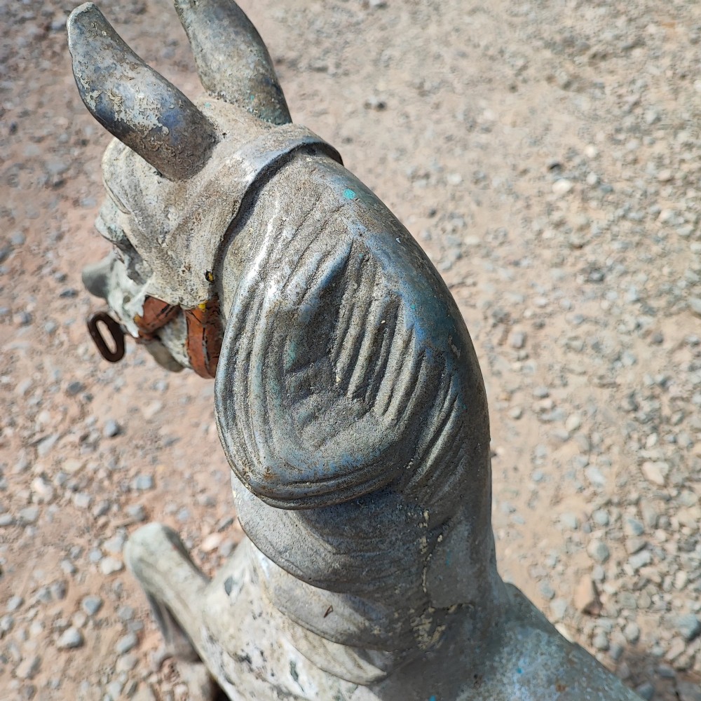 A cast metal antique carousel horse displaying distressed blue, red, and white paint with a weathered surface patina. View II