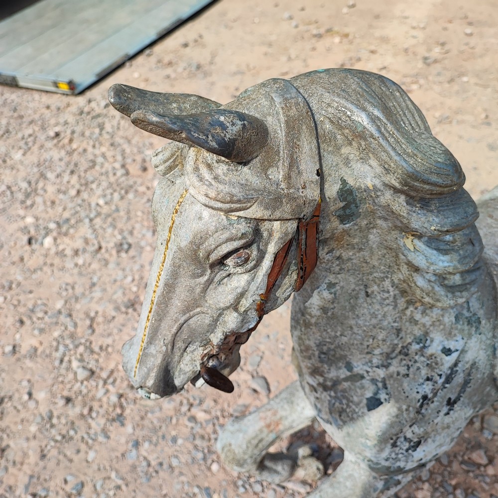 A cast metal antique carousel horse displaying distressed blue, red, and white paint with a weathered surface patina. View VI