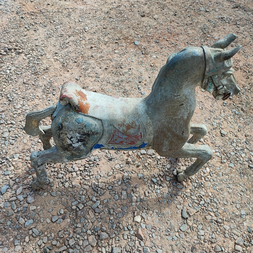 A cast metal antique carousel horse displaying distressed blue, red, and white paint with a weathered surface patina. View X