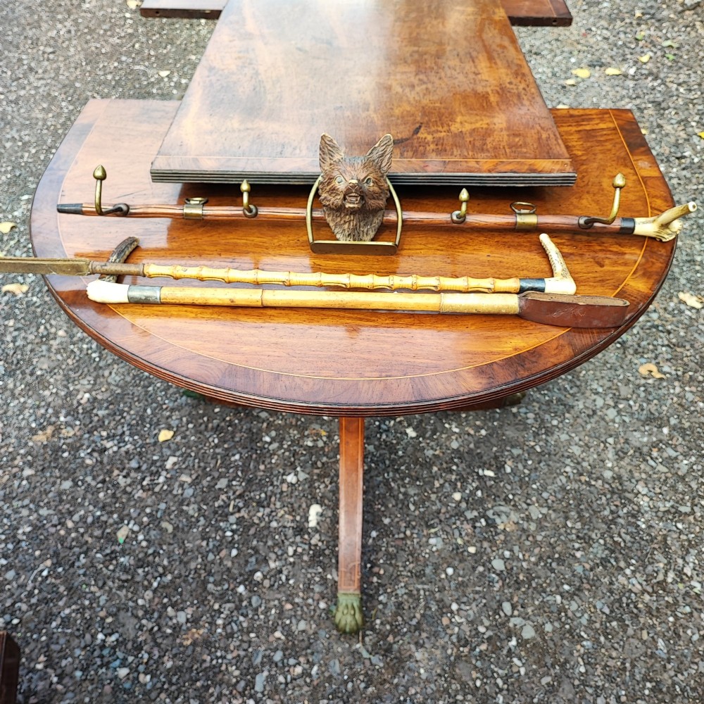 A carved wooden fox head whip rack mounted inside a brass stirrup frame with horizontal brass hooks on a wooden shaft. View III